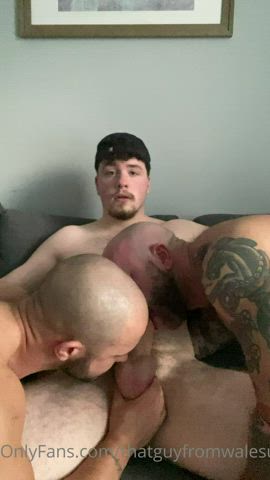 Two guys servicing his cock