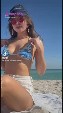 Beach babe flashing behind a man sunbathing