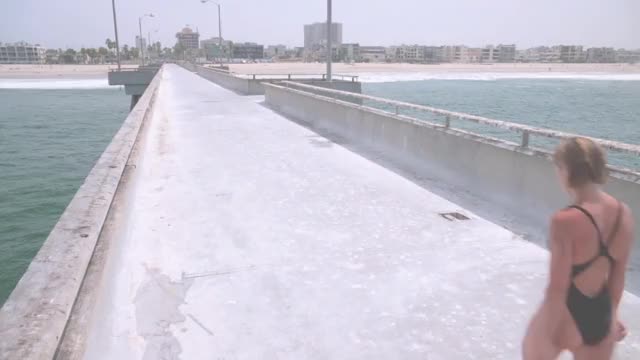 Nicole Eggert - Baywatch - S3E4 - backstory in black swimsuit walking down pier;