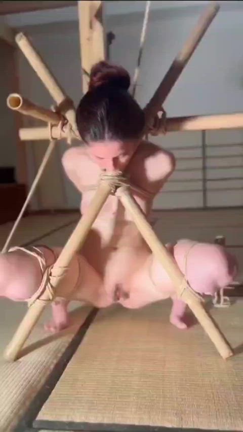 Moaning from pain in tight bamboo frame bondage