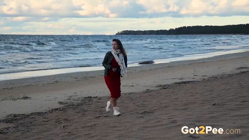 Lady pulls off panties to pee against the wind at the beach