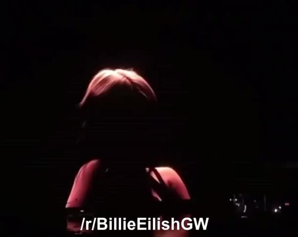 Billie Eilish taking her top of at a live show