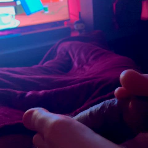 She uses her toes to play with my cock while she watches cartoons