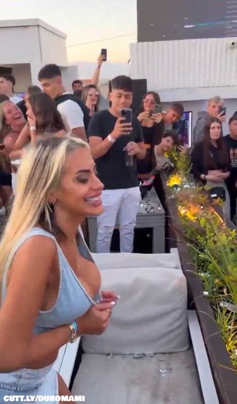 Flashing public blonde in the crowd shows her tits